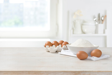 Baking ingredients on wooden table over defocused kitchen window background