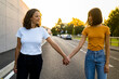 © Westend61 - Young lesbian couple looking at each other while holding hands on road