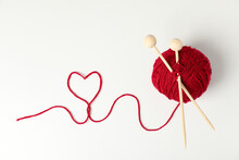 Red Ball Of Yarn And Knitting Needles On White Background