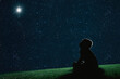 child sit on the grass at night and look at the christmas night sky