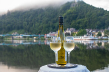 Tasting of white quality riesling wine served on outdoor terrace in Mosel wine region with Mosel river and old German town on background, Germany