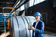 © Westend61 - Male engineer with hardhat holding globe while standing in steel mill
