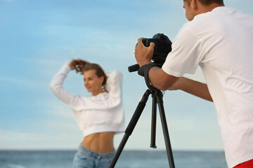 Sticker - Photographer taking picture of model with professional camera near sea