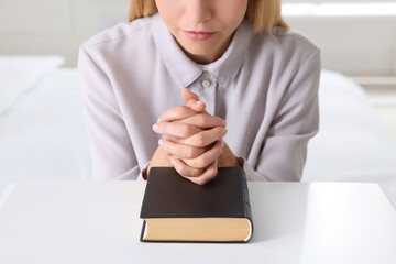 Wall Mural - Religious young woman with Bible praying at home, closeup