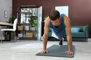 Poster - Handsome man doing high plank exercise on floor at home