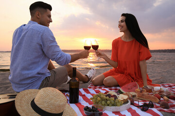 Wall Mural - Lovely couple having picnic near river at sunset