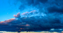 Panorama Of Blue Cumulus Clouds Illuminated By The Setting Evening Sun