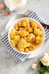 Wall Mural - Baked cauliflower in a white bowl on a gray background. Homemade baked cauliflower with butter, cream and garlic. Tasty vegetarian food.