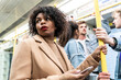 © william87 - Busy tube, people commuting, black woman holding phone