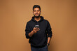 © Тарас Нагирняк - Young indian man in black hoody surfing his mobile phone on background