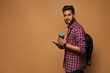 © Тарас Нагирняк - Handsome hindu man looking to camera with coffe to go and backpack on pastel background copy space