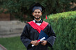 Handsome indian graduate in graduation glow with diploma looking at camera