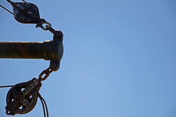 Suspended boat anchor with blue sky background and copy space.