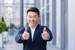 © Liubomir - broker asian businessman in business suit happy looking at camera and showing thumbs up