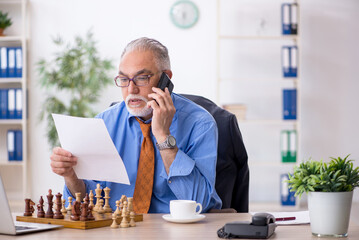 Sticker - Old businessman playing chess at workplace