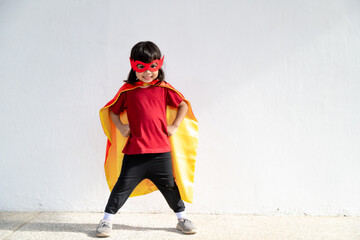 Little child girl plays superhero. Child on the white background. Girl power concept