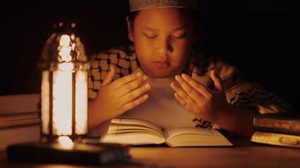 Wall Mural - A little Asian Muslim boy is sitting and reading the Quran. The peace in the mosque makes it an energetic atmosphere of faith.