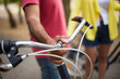 © KAMPUS - Close-up of mature man gripping bike handlebar. Male cyclist dating with woman outdoors. Active seniors concept