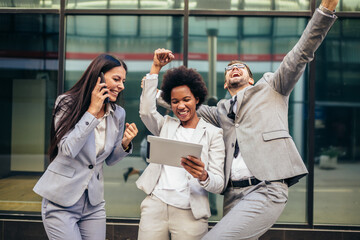 Wall Mural - Business team celebrating a triumph, looking at digital tablet.