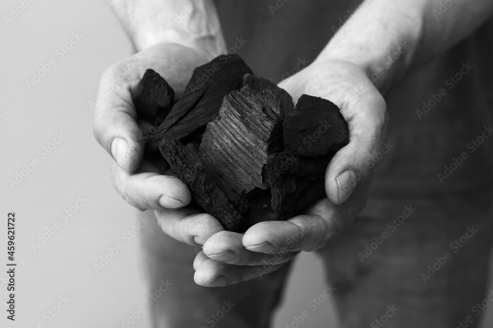 Black charcoal in male hands, closeup