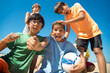 Portrait of excited preteen soccer players with ball looking at camera and shouting on beach. Multiethnic boys playing football at seaside. Summer vacation and friendship concept