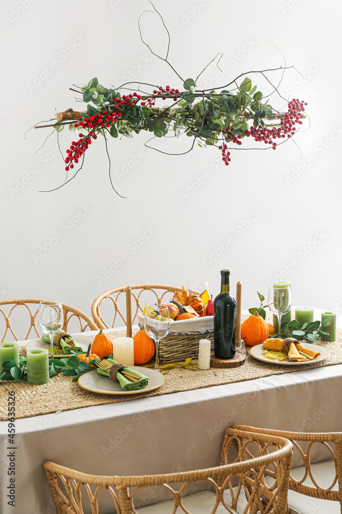 Beautiful table setting with fresh pumpkins and leaves near light wall