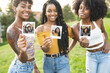 © Westend61 - Smiling young women showing photographs at park