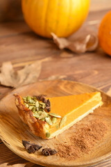 Plate with piece of delicious pumpkin pie on wooden background