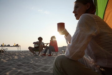 Poster - Friends resting on sandy beach. View from camping tent