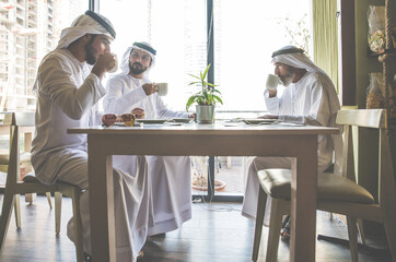 Wall Mural - Three business men having a tea in Dubai wearing traditional emirati clothes