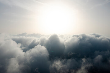 Wall Mural - View from above, drone point of view, stunning aerial shot of some fluffy clouds with a bright sun.