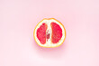 Half of fresh grapefruit on pink background. Symbol of vagina. Gynecology, female intimate health, menstruation concept.