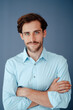 © Westend61 - Young businessman with arms crossed against blue background
