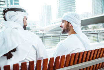 Wall Mural - Two young businessmen going out in Dubai. Friends wearing the kandura traditional male outfit in Marina