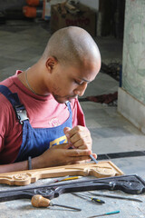 Wall Mural - Vertical shot of a Cuban person restoring a piece of wooden vintage furniture