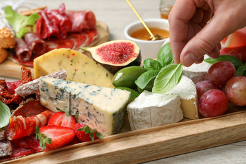 Wall Mural - Woman taking basil from board with different appetizers, closeup