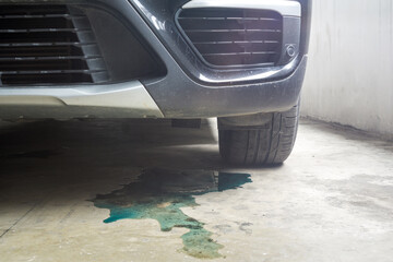 Car parked with water coolant liquid leak out from the engine down on the floor background