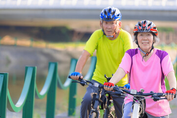 Wall Mural - Happy  senior couple exercising with bicycles in the park