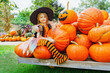 child girl als little cute witch with pumpkin outdoors in halloween