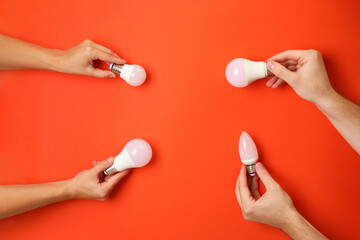 Wall Mural - Hands hold energy saving bulbs on red background