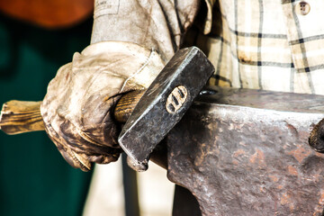 Wall Mural - Close up on a blacksmith holding a hammer on an anvil.