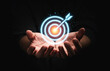 © Dilok - Businessman holding virtual dartboard with arrow ,setup Business Achievement objective target concept.