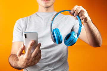 man holding headphones and phone on orange background