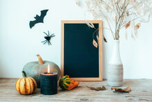 Halloween Composition With Blackboard, Pumpkins, Candle And Dried Flowers In Vase, Bat And Spider. Festive Background, Close Up. Copy Space