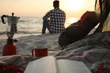 Wall Mural - Man enjoying sunset on beach, view from camping tent