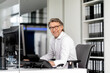 © Westend61 - Happy male professional sitting at desk in office
