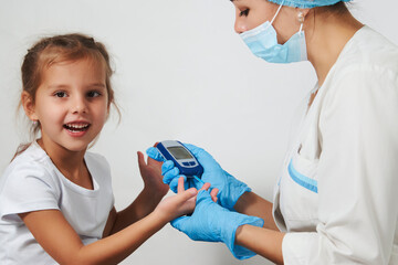 Wall Mural - Young nurse doctor measuring blood sugar level of girl