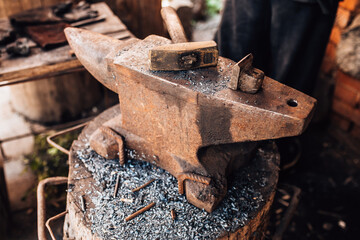 Heavy old rusty anvil in a forge and a hammer on it - craft production metal processing and forging steel household items and weapons