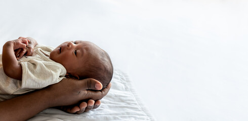 Baby black skin newborn son is 12-day-old lying on the hand of father with happy, On white background and space, concept to African family and black skin newborn