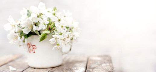 Wall Mural - Still life with cup and bouquet of branches with apple blossoms. White petals of flowering trees that fell on concrete